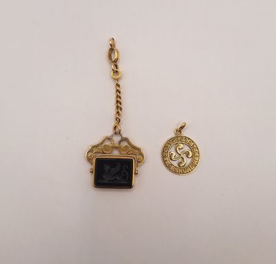 un pendentif en or orné d'une pierre noire et d'une pièce de monnaie