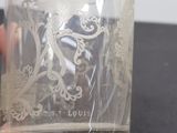 Quelqu'un tient sur une table un verre orné d'un oiseau.