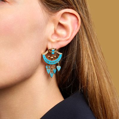 a woman wearing a pair of earrings with turquoise and gold details