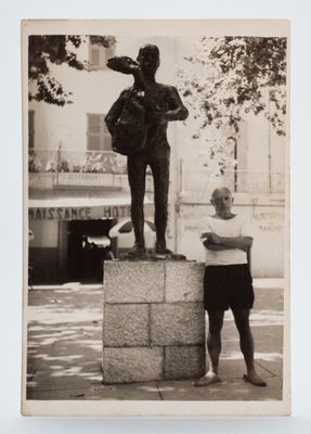black and white photograph of a man standing next to a statue of a man holding a tennis racquet