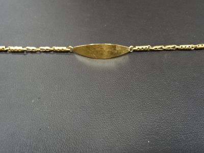 gros plan d'un bracelet en or sur une surface noire