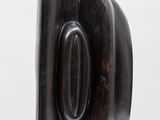 a black sculpture on a white shelf with a white background