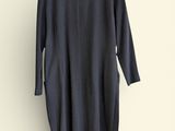 black dress hanging on a hanger against a white wall
