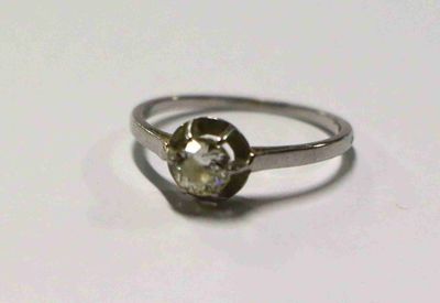 une bague sertie d'un diamant, posée sur une surface blanche