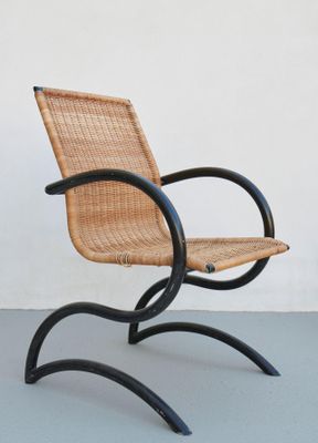 une image représentant une chaise aux pieds en métal noir et à l'assise en osier