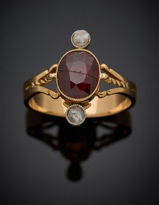 une bague en or sertie d'une pierre rouge et de deux diamants blancs