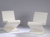 two white chairs sitting next to each other on a white surface