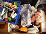 a man holding a baby in a box full of toys