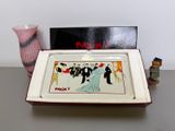 a small tray with a painting on it next to a vase