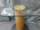 une table en verre avec un piètement en bois et un bol posé dessus