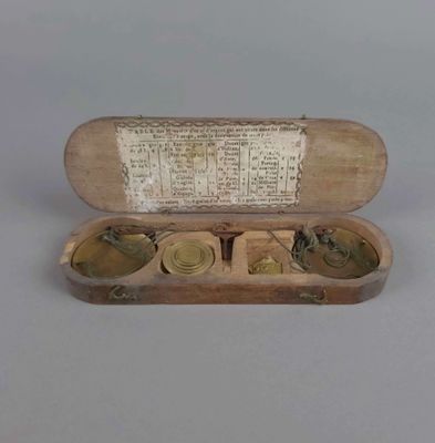 une petite boîte en bois contenant trois pièces en laiton