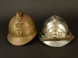 pair of firemen ' s helmets on a black surface with a black background