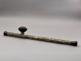 une pipe noire et dorée posée sur une surface blanche