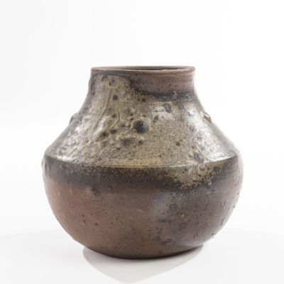a brown vase that is sitting on a white surface