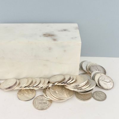 un bloc de marbre blanc posé sur une table, sur lequel se trouvent des pièces de monnaie