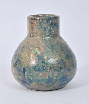 un vase bleu et vert posé sur une surface blanche