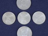 four silver coins on a blue cloth with a white background