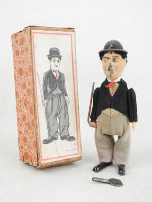 une petite figurine représentant un homme debout à côté d'une boîte