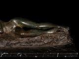 statue of a woman laying on a rock on a black background
