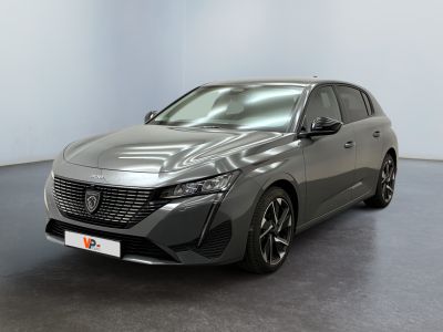 La voiture grise est garée dans une grande pièce au sol noir.