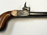 un vieux pistolet avec une poignée en bois sur une surface blanche