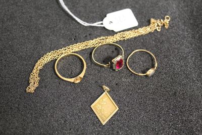 Plusieurs bagues et un collier sont posés sur une surface noire