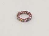 La bague est composée de pierres multicolores et repose sur un fond blanc.