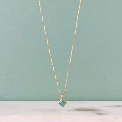 a gold chain necklace with a blue stone pendant on it