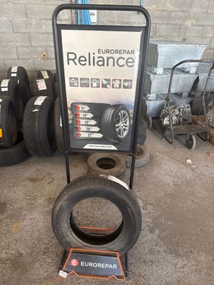une enseigne d'un atelier de réparation de pneus avec des pneus posés par terre