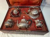 a silver tea set in a case on a table