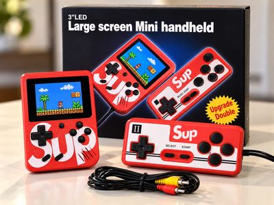 une petite console de jeux rouge posée sur une table à côté d'une boîte