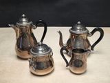 two silver teapots sitting on top of a table next to each other