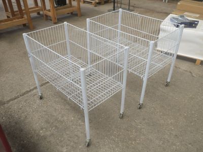 une cage métallique blanche posée au sol, munie de roulettes
