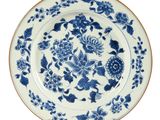blue and white plate with flowers and birds on it on a white background