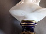 a blue vase with a white bust on top of it