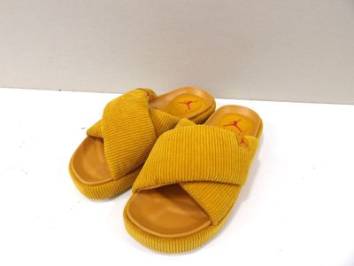 des chaussons jaunes ornés d'un smiley, posés sur une surface blanche