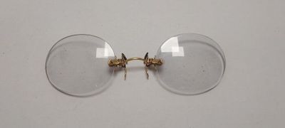 une paire de verres transparents à monture dorée posés sur une surface blanche