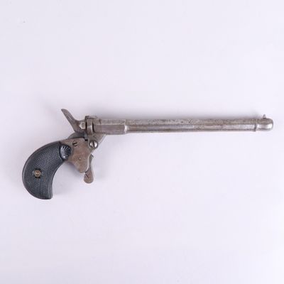 un vieux pistolet avec une poignée en bois sur une surface blanche