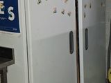 un réfrigérateur blanc au milieu d'une pièce, à côté d'une borne d'incendie