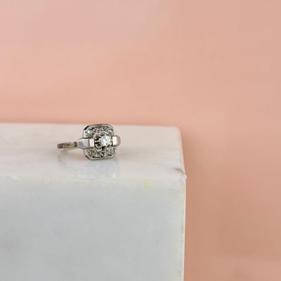 un gros plan d'une bague en diamant posée sur un bloc blanc