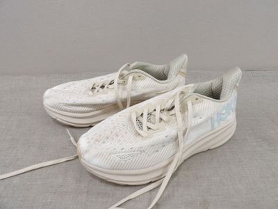 une paire de baskets blanches à lacets posées sur une surface grise