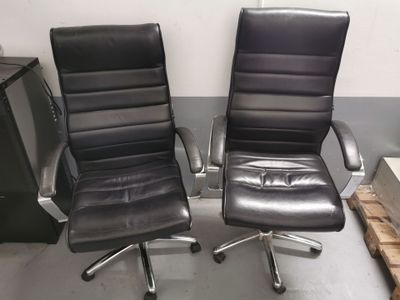 pair of black leather office chairs sitting in a warehouse area