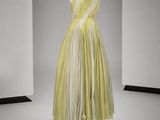 une photo d'une robe jaune et blanche posée sur un présentoir pour mannequin