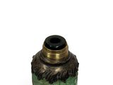 a green vase with a black lid on a white surface