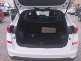 the back of a white car with its trunk open in a parking lot