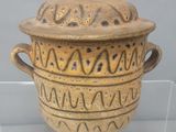 un grand vase muni d'un couvercle, exposé dans une vitrine