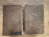 two old books sitting on top of a wooden table next to each other