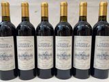 six bouteilles de vin sont alignées sur une table