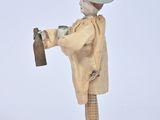a figurine of a man in a hat and coat holding a bottle