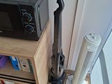 a black and silver vacuum on the floor next to a book shelf